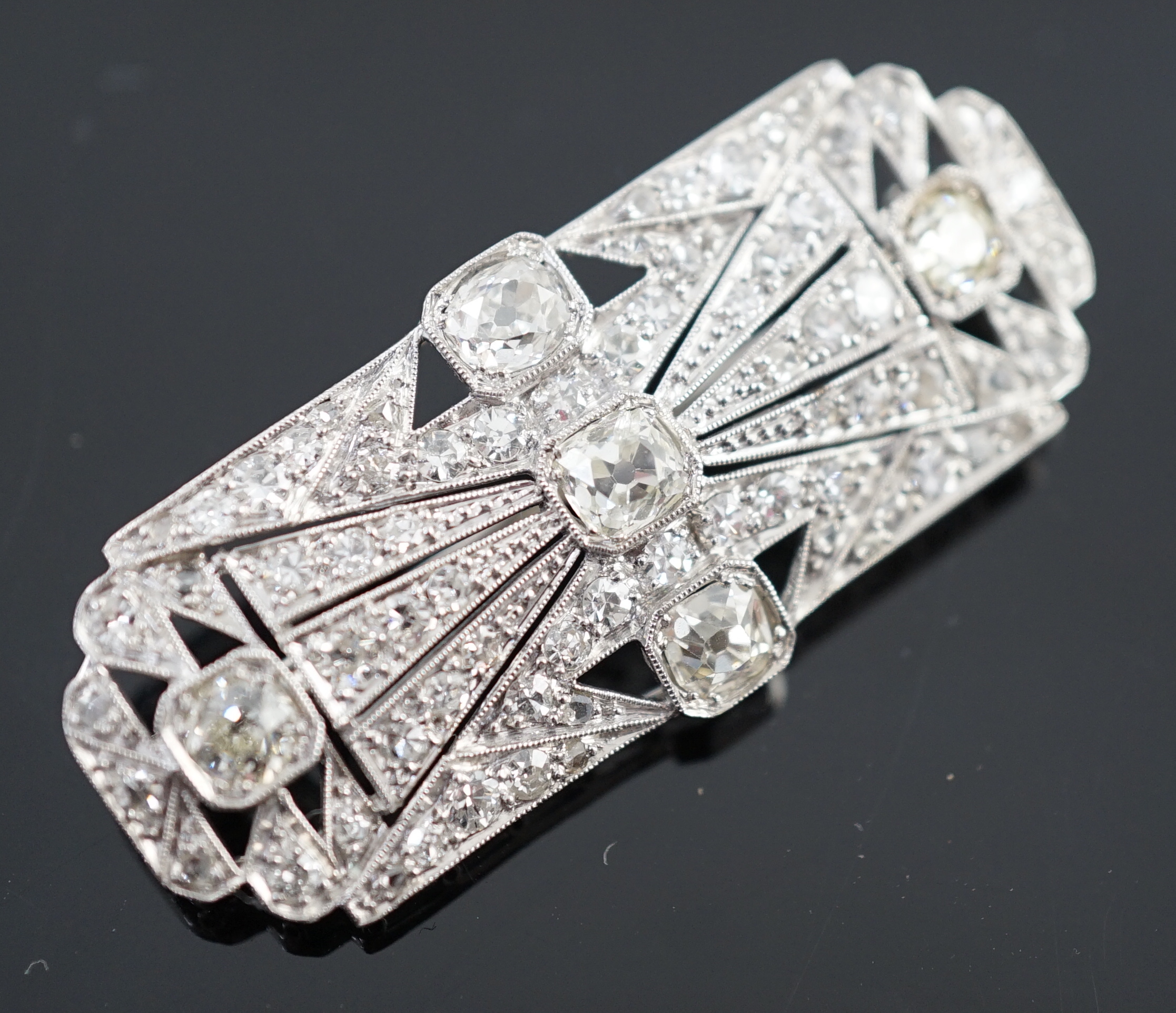 An Art Deco pierced platinum and millegrain set diamond cluster shaped rectangular brooch